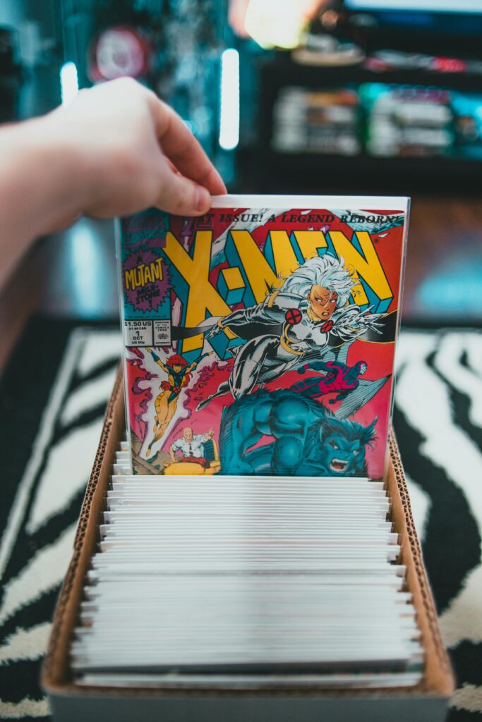 A hand selecting an X-Men comic from a collection in a cardboard box indoors.